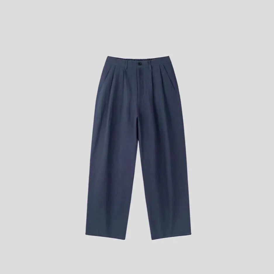 Man wearing apricot wide-leg cotton linen trousers with a mid waist and zip fly.