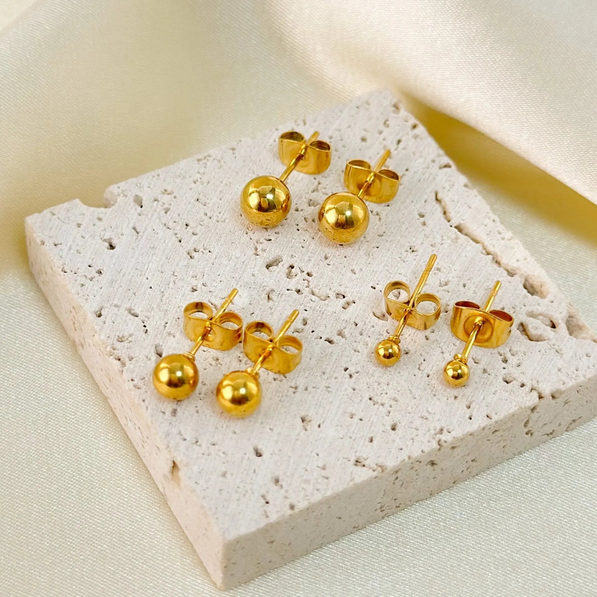 Stainless steel ball stud earrings in gold and silver, shown in 3mm, 4mm, 5mm, and 6mm sizes