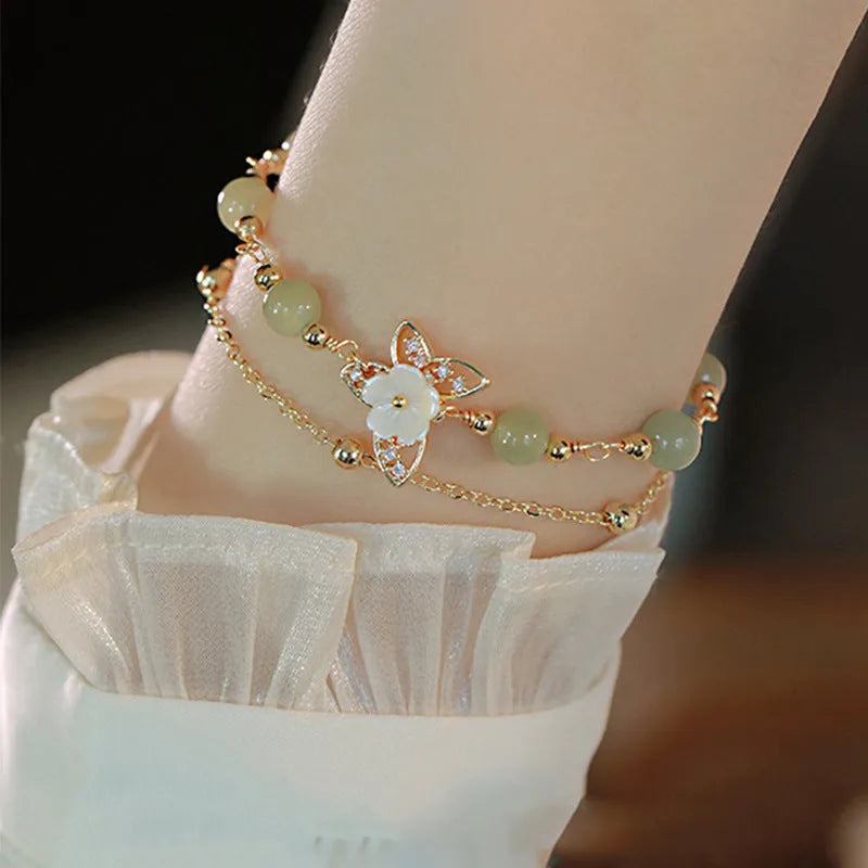 Yellow gold electroplated copper bracelet with genuine Hetian jade Bells of Ireland butterfly charm for women.