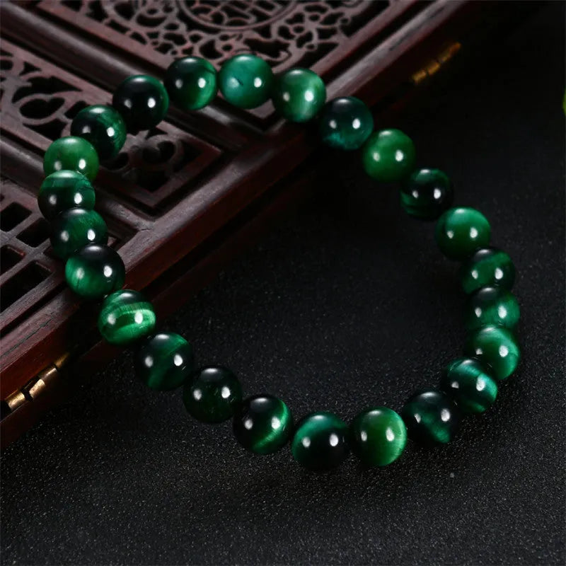 Polished green tiger eye stone bracelet with geometric beads on a wrist, showing size options.