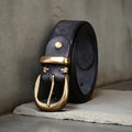 Men's black cattlehide leather belt with copper pin buckle on a pair of jeans