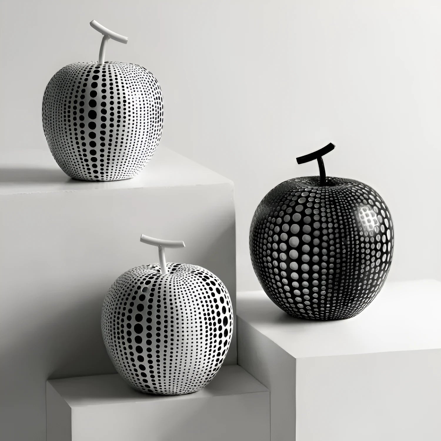 Decorative resin apple and pear crafts in white, orange, black, and blue on a shelf.