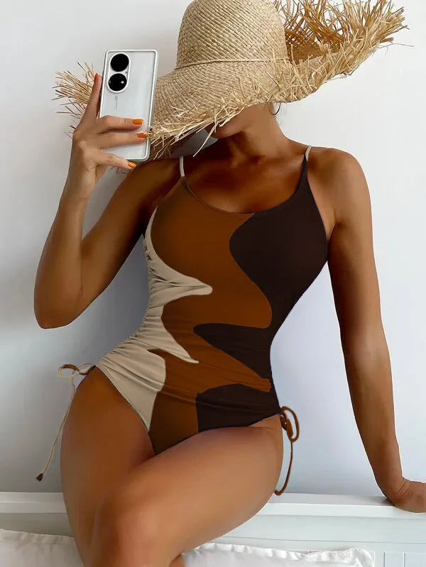 Women's blue sleeveless backless one-piece swimsuit on a hanger showing striped print detail.