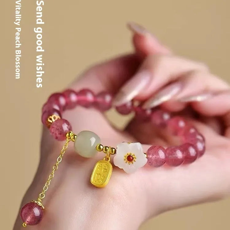 Handmade strawberry quartz crystal bracelet with peach blossom design on a wrist.