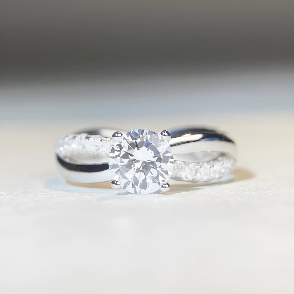 A geometric twisted silver ring with a 1 karat moissanite stone in a four-claw setting.