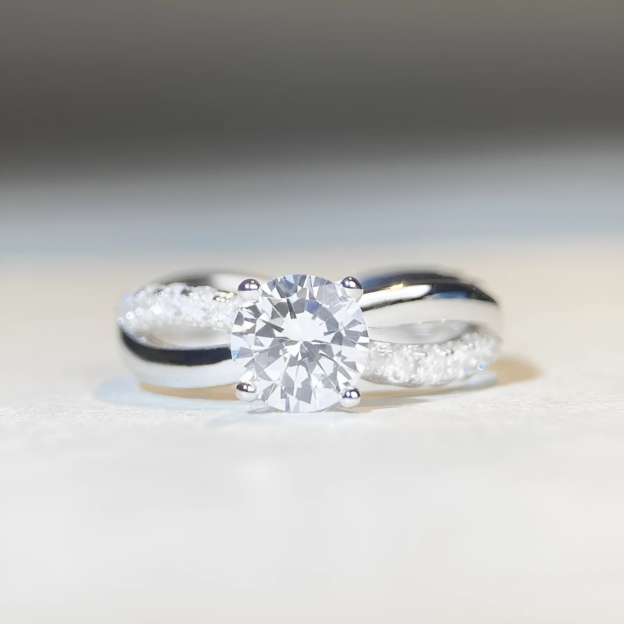 A geometric twisted silver ring with a 1 karat moissanite stone in a four-claw setting.