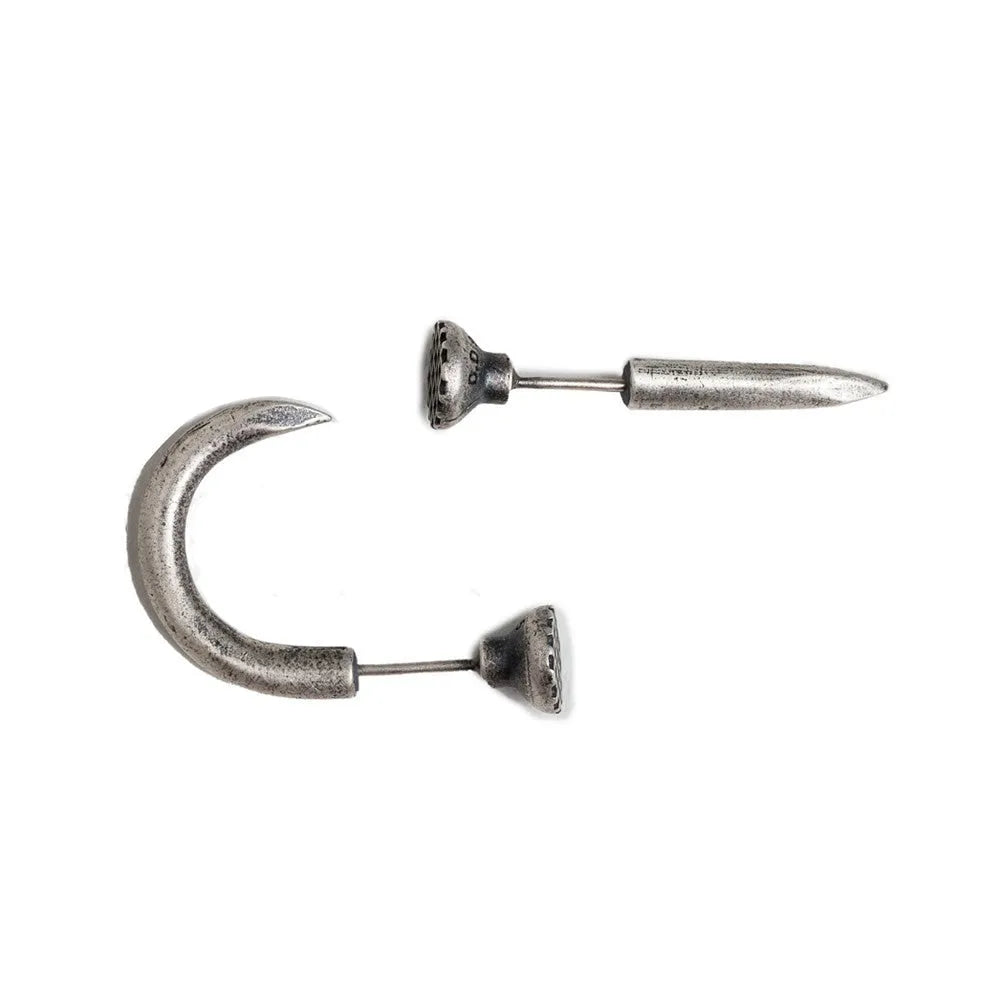 Close-up of a sterling silver punk stud earring with a retro nail design on an ear.