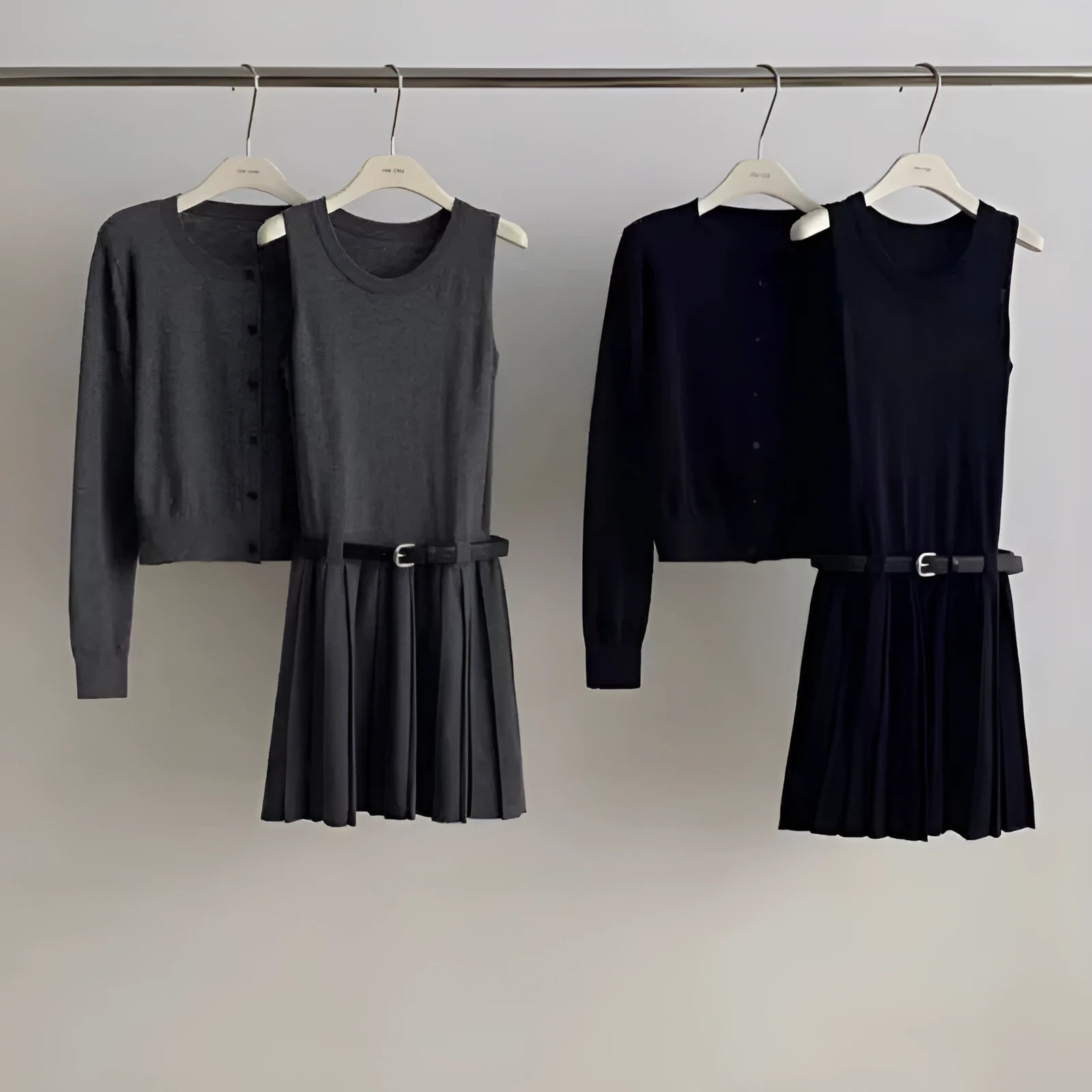 Women's black knitted two-piece set with long-sleeve cardigan, pleated vest skirt, 3D pattern, and a belt.
