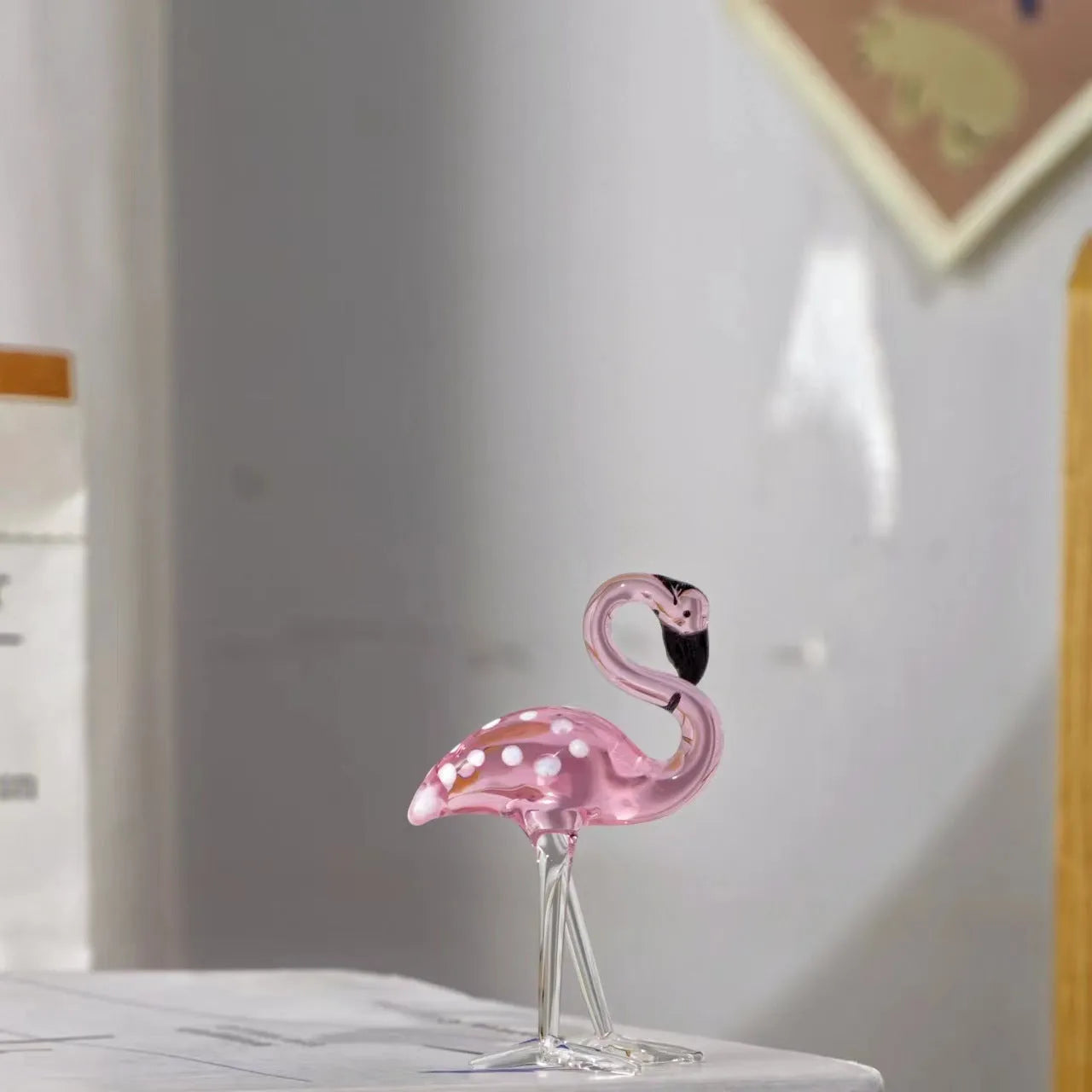 Pink crystal flamingo decorative ornament on a table, modern minimalist style.