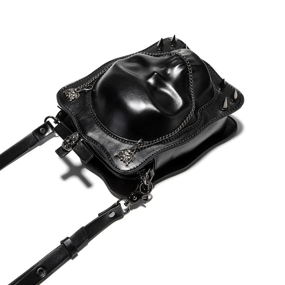 Black square crossbody bag with embossed skull design, chain accents, and zip opening