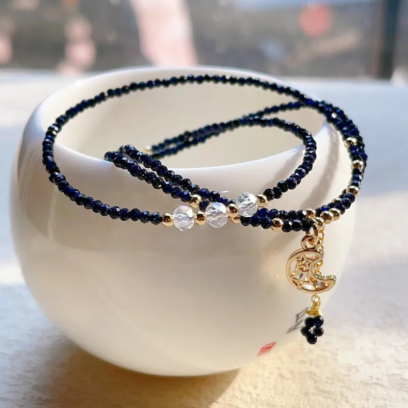 Close-up of a women's multi-layer bracelet with three interlinked rings made from blue and gold cut sand stone.