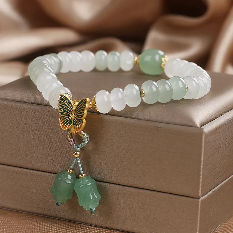 Green crystal abacus bead bracelet with butterfly charm and tassel detail, 17 cm length
