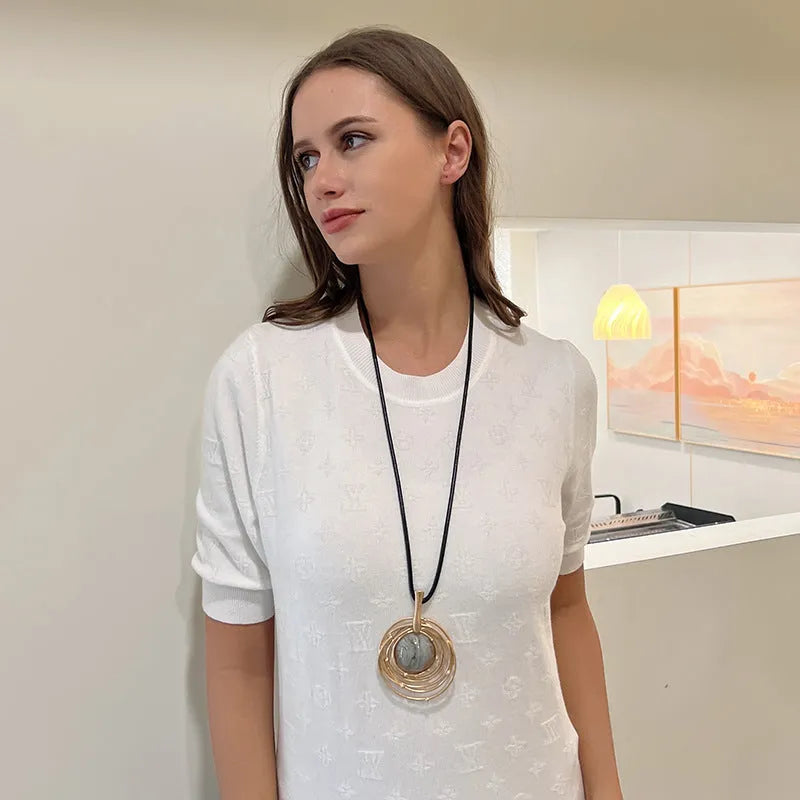 Large round gold geometric pendant on a long adjustable snakeskin rope chain necklace for sweaters