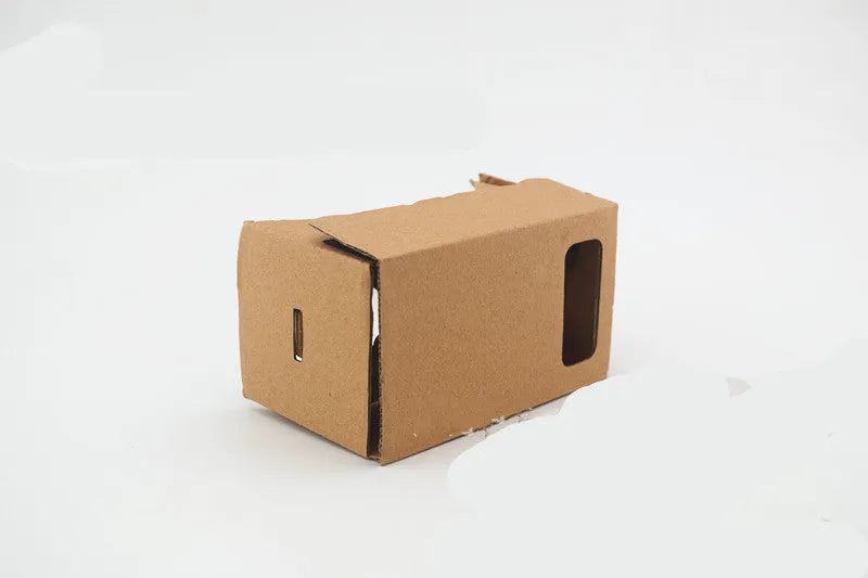 Foldable pink and white cardboard VR glasses headset with lenses and rubber head strap for smartphones.
