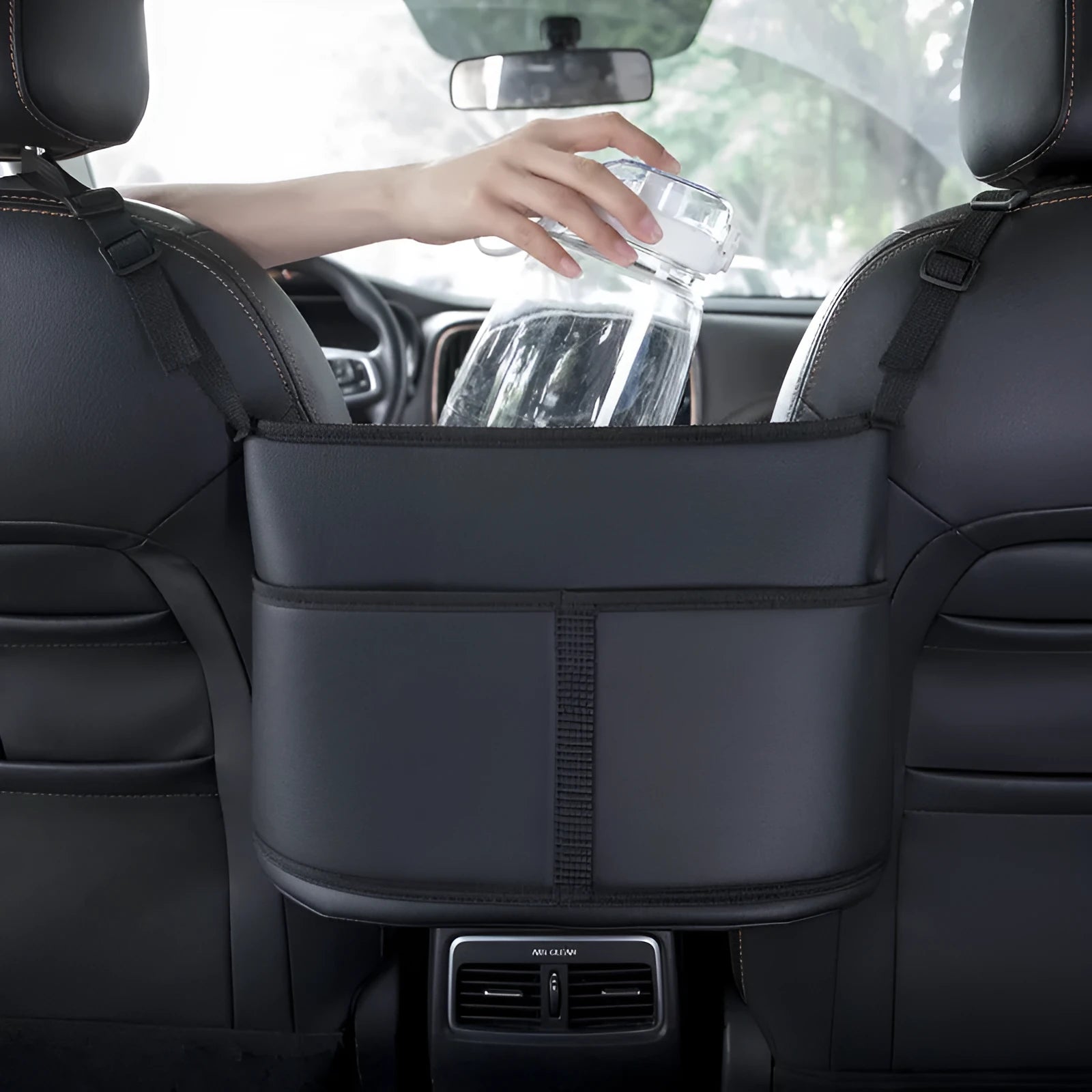 Black leather car seat storage bag with carbon fibre pattern, shown fitting between car seats.