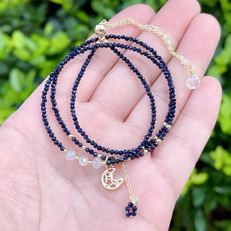 Close-up of a women's multi-layer bracelet with three interlinked rings made from blue and gold cut sand stone.