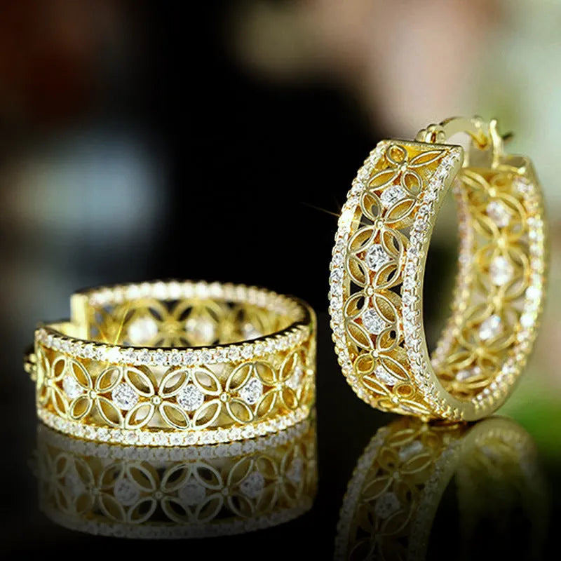 A pair of gold-coloured geometric clip-on earrings with horse, eye, flower and butterfly motifs on a copper base.