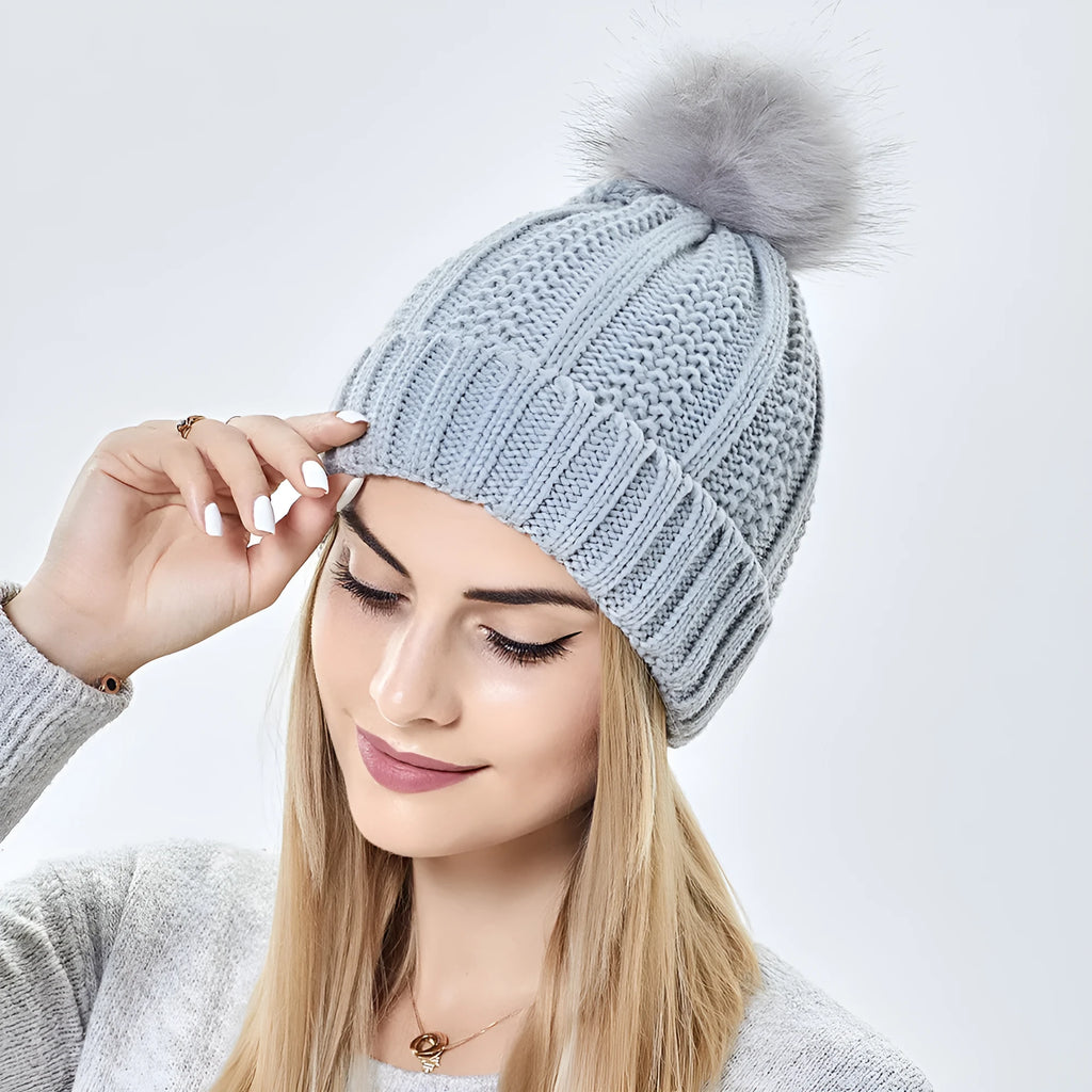 Women's knitted beanie hat with satin lining and a faux fur pom pom in a choice of eight colours.