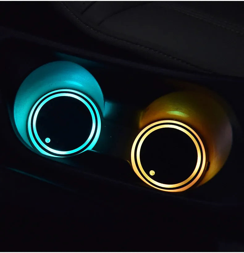 Colourful LED light-up coaster for car cup holder with USB cable on a car centre console.