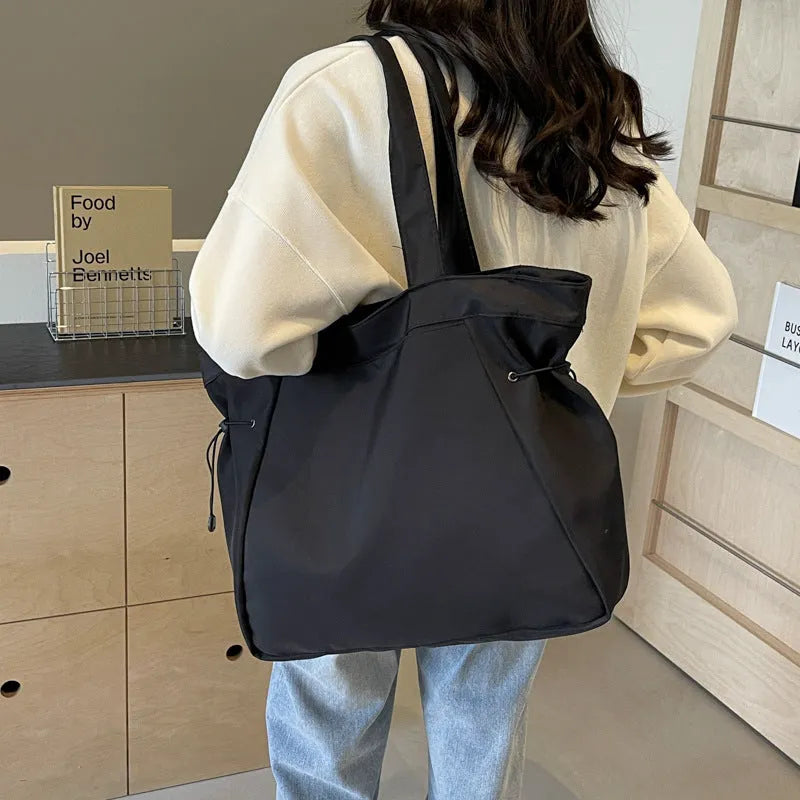 A soft folding Oxford cloth tote bag in a choice of five colours: black, light grey, dark grey, brown, and purple.