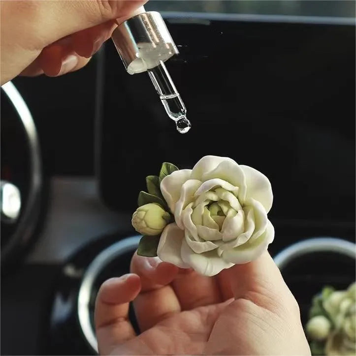 Solid jasmine car perfume diffuser clipped on a car air vent in off white or fresh green.