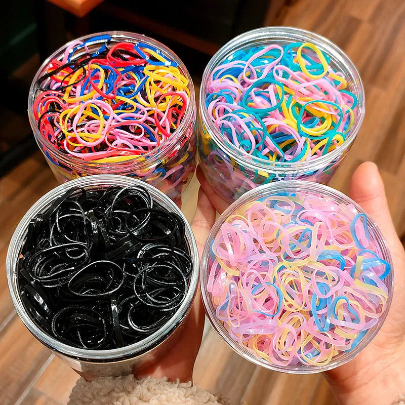 Multi-colour TPU baby hair elastic bands spilling from a reusable container.