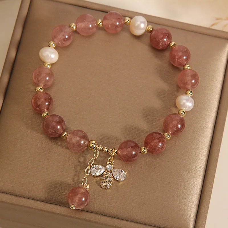Women's adjustable bracelet with pink strawberry quartz stones, white freshwater pearls, and zircon accents on a wrist.