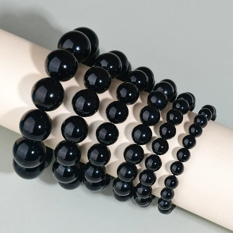 Hand-woven black obsidian bracelet with round beads, shown as a couple's set on a wrist.