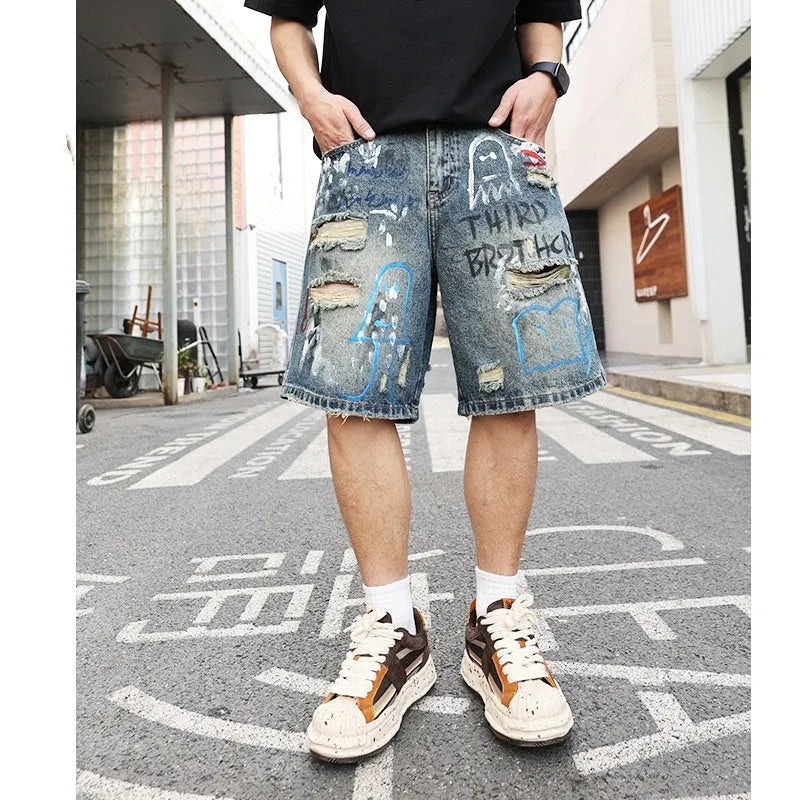 Blue men's denim jeans shorts with graffiti print and ripped details, showing straight leg and zipper fly.