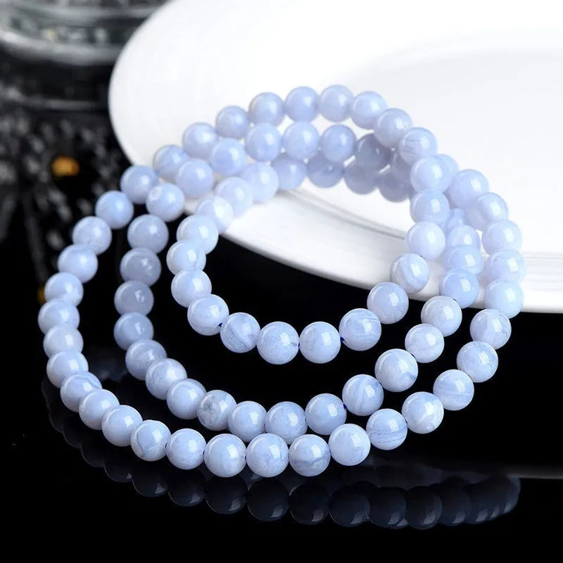 Blue striped agate bead bracelet with Ruyi charm on a wrist.