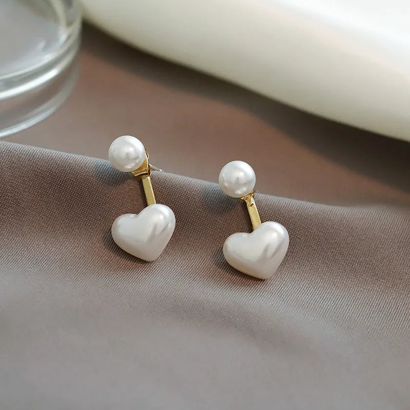 Women's heart-shaped stud earrings with a pearl-like centre in electroplated alloy, Korean style.