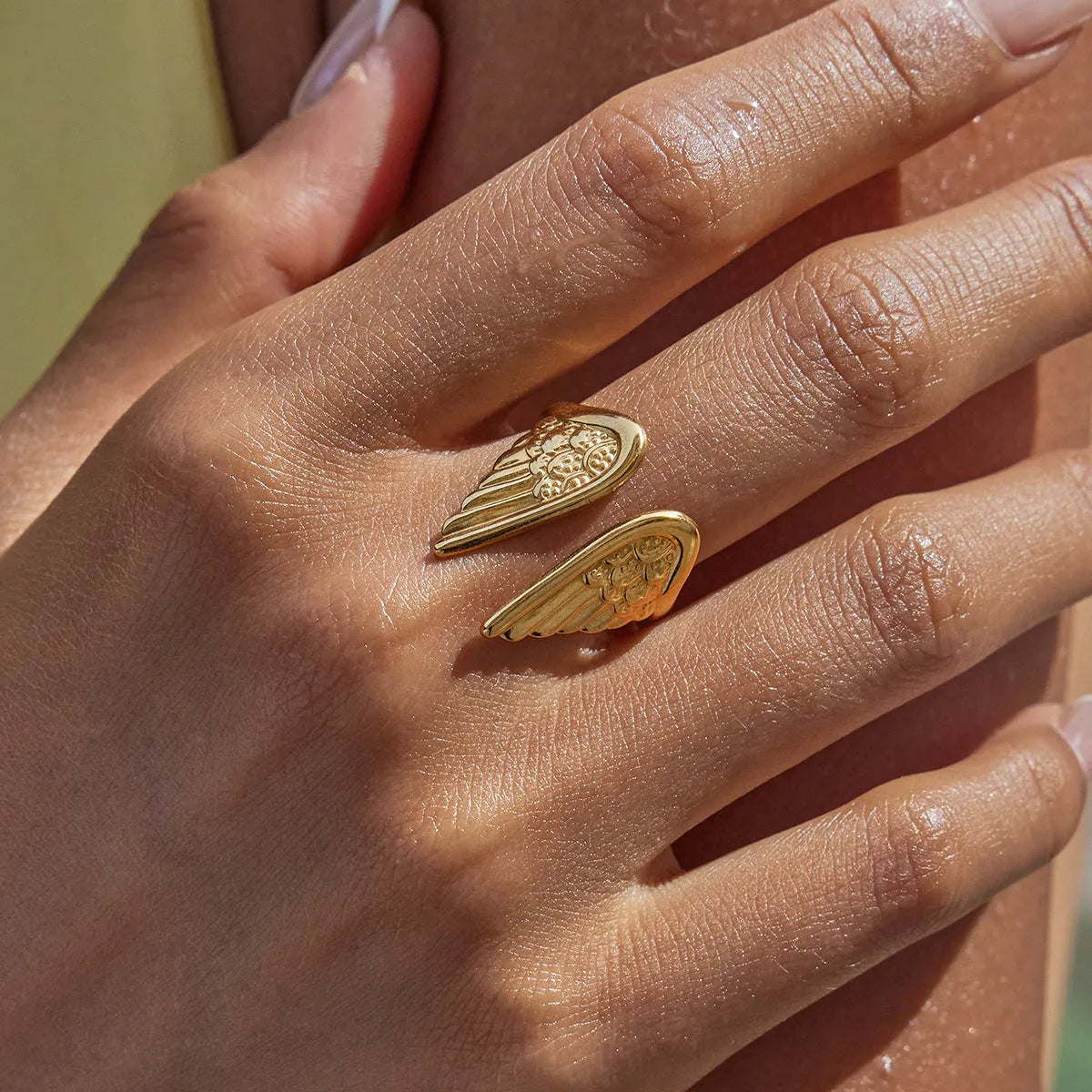 Stainless steel wings design ring with an adjustable opening mechanism on a neutral background.