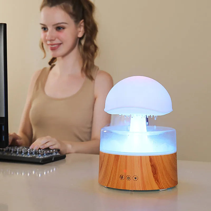 White cloud-shaped humidifier with LED lighting and raindrop simulation on wooden surface