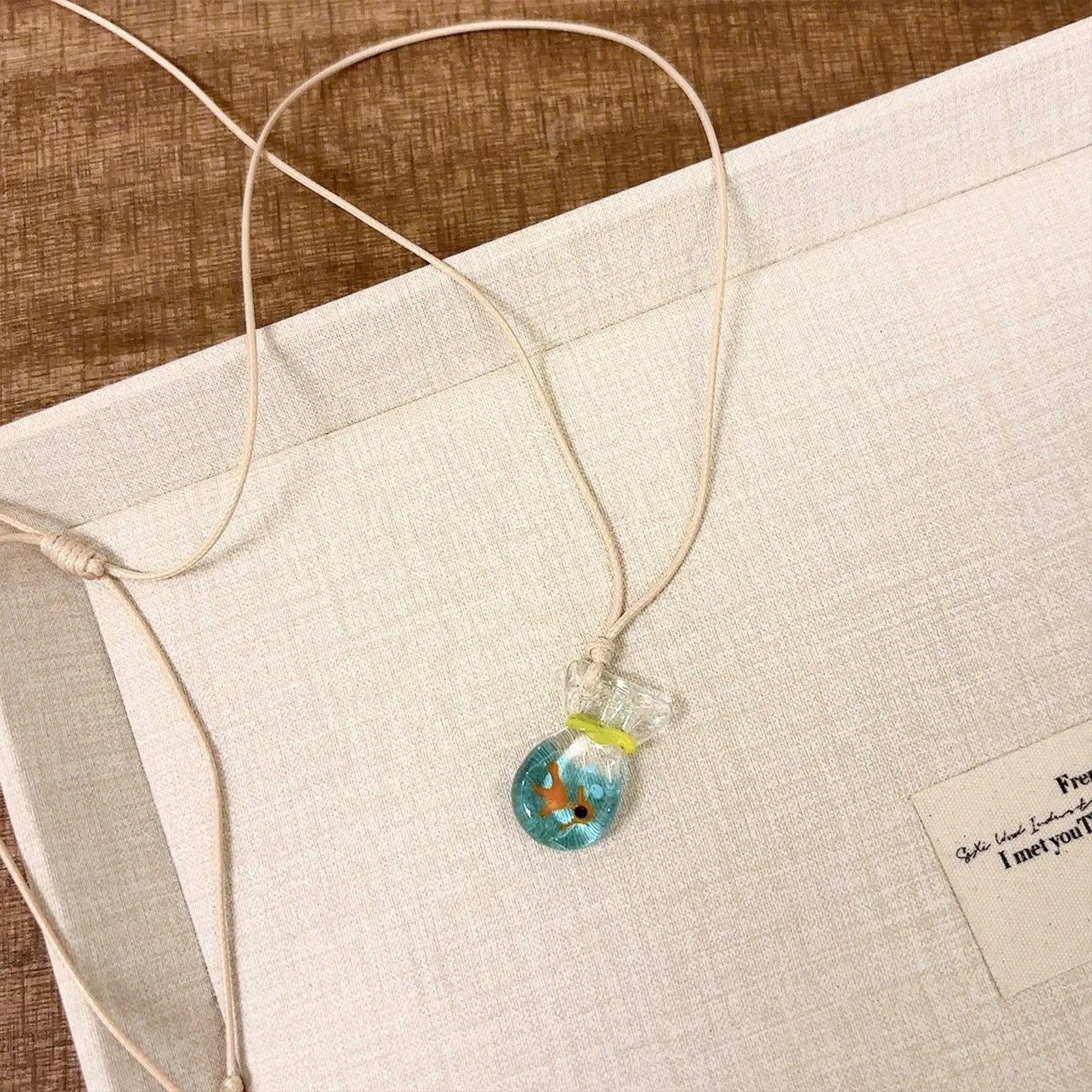 Women's coloured glaze small fish lucky bag pendant on a cotton linen clavicle chain necklace.