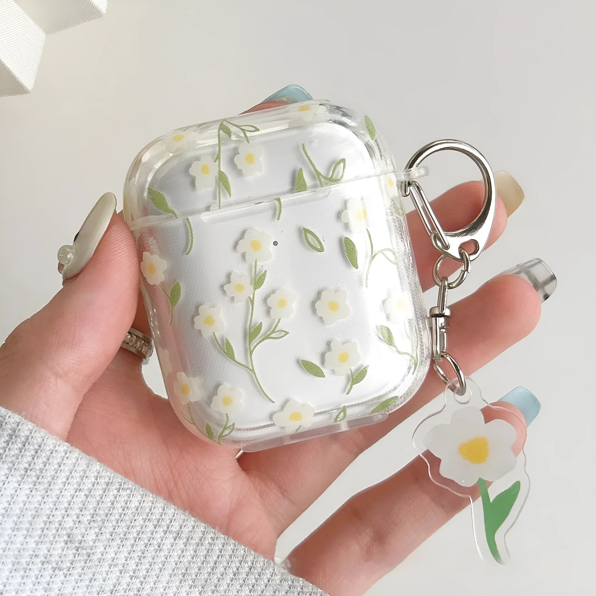 Transparent white floral patterned soft TPU protective case for Apple AirPods on a table.