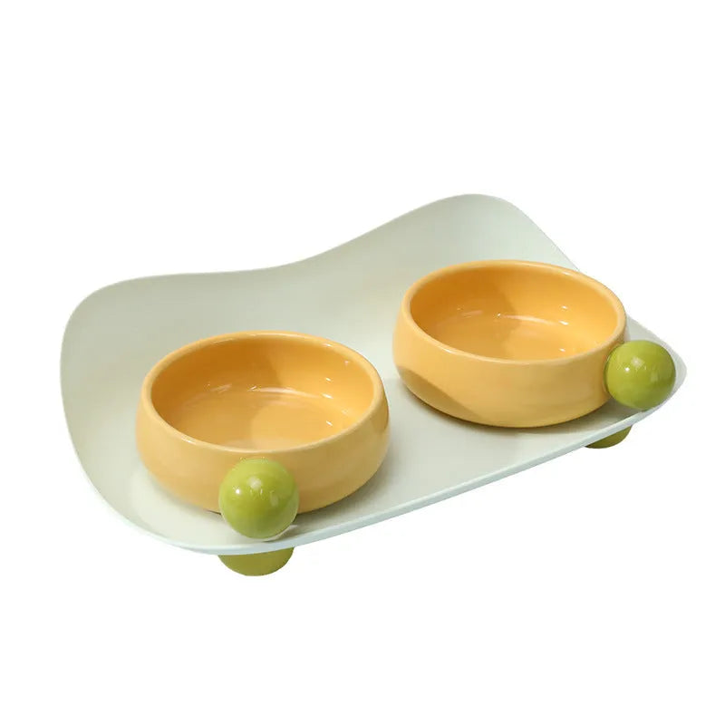 Raised ceramic dual pet feeding bowl in pink, yellow, or pink yellow with non-slip base