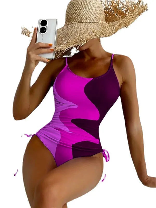 Women's blue sleeveless backless one-piece swimsuit on a hanger showing striped print detail.