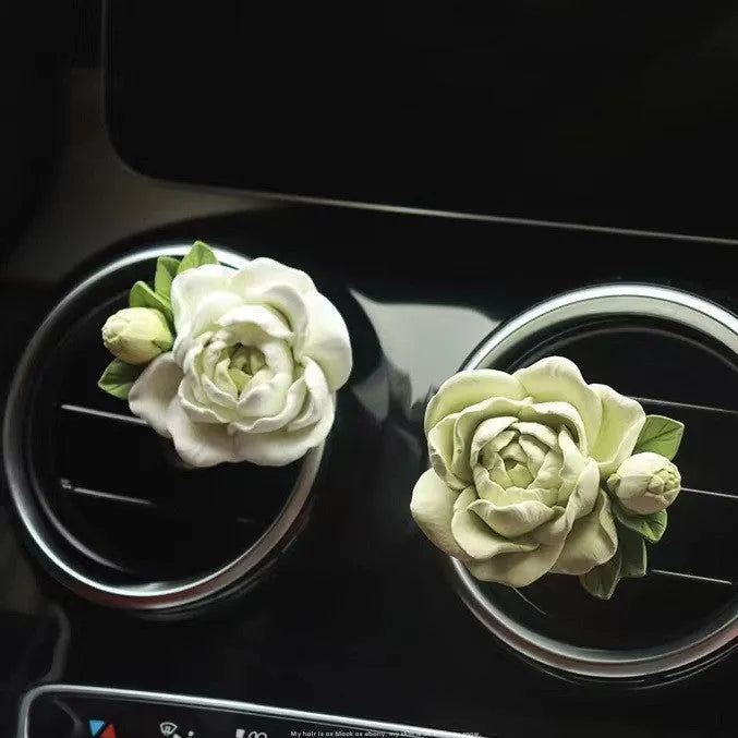 Solid jasmine car perfume diffuser clipped on a car air vent in off white or fresh green.