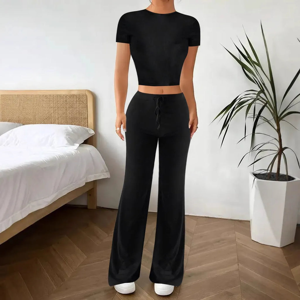 Women's black high waist trousers and short sleeve t-shirt co-ord set laid flat.