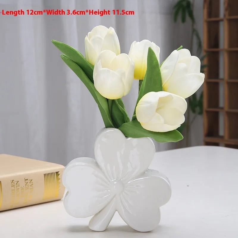 European style white porcelain ceramic vase in four colour options on a desktop.