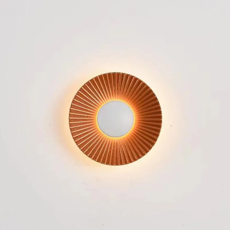 Round white and gold aluminium wall lamp mounted on a wall, LED light source visible.