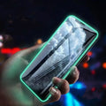 Luminous full cover tempered glass screen protector glowing green in the dark for iPhone.