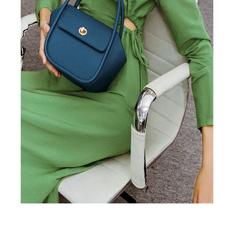 Wing-shaped women's leather handbag with latch closure and cross-body strap in available colours.