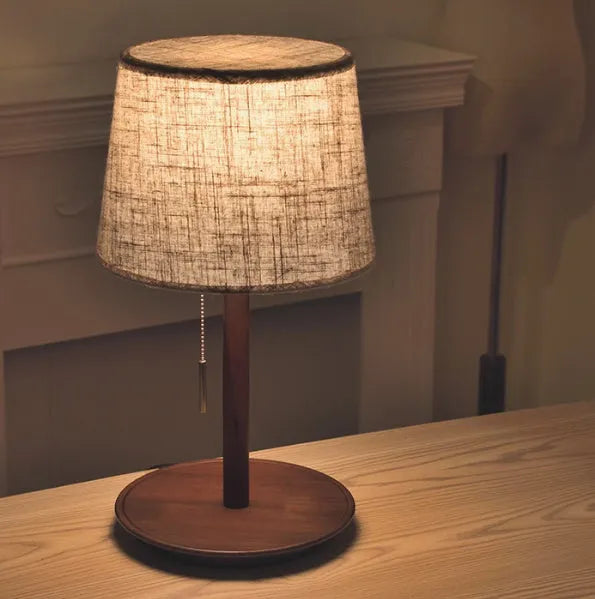 Walnut colour solid wood desk lamp with a white cloth shade and black cable switch.