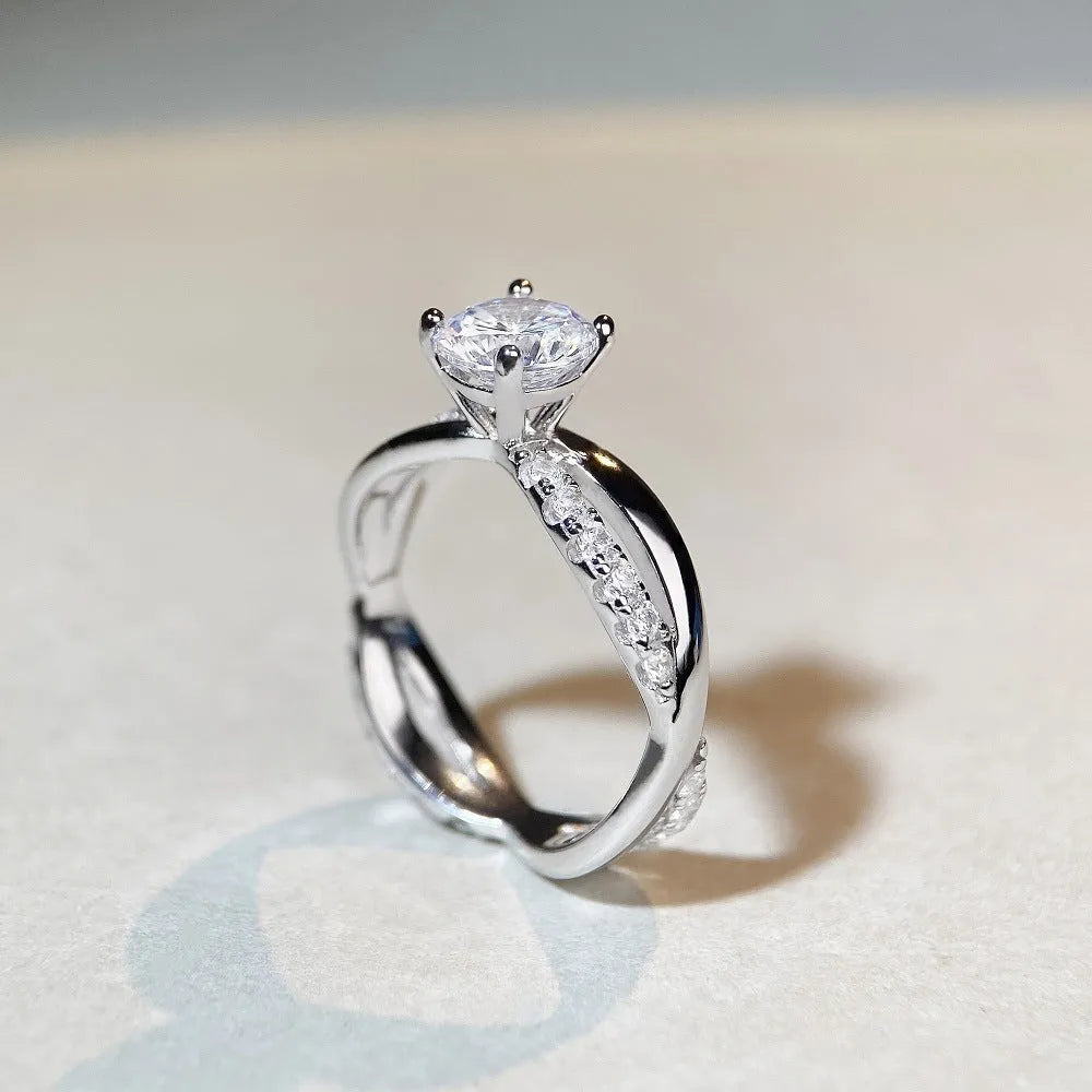 A geometric twisted silver ring with a 1 karat moissanite stone in a four-claw setting.