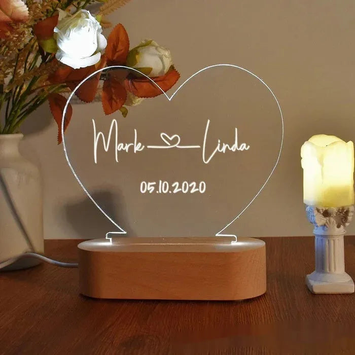 Custom acrylic night light with engraved names illuminated by LED base on bedside table