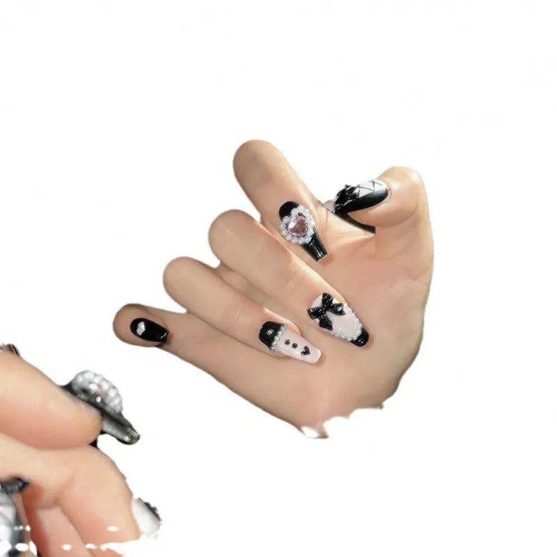 Detachable artificial nails with hand-painted black and pink heart design and cat's eye finish in four sizes