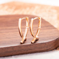 A pair of rose gold coloured cross-shaped stud earrings on a plain background.