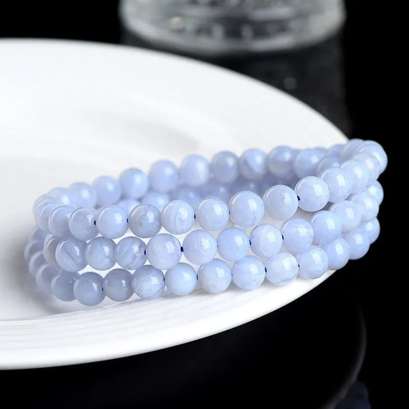 Blue striped agate bead bracelet with Ruyi charm on a wrist.
