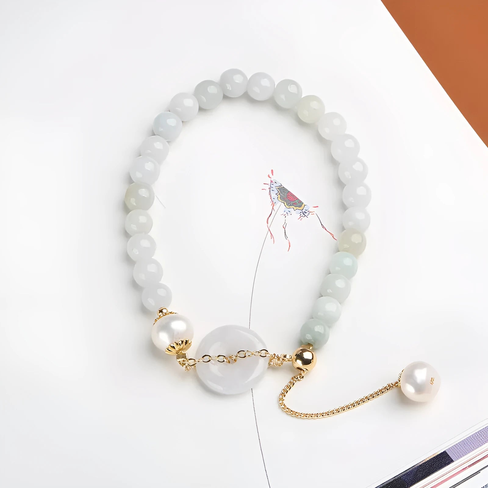 Close-up of a women's bracelet with a jade peace symbol buckle on a string of freshwater pearls.